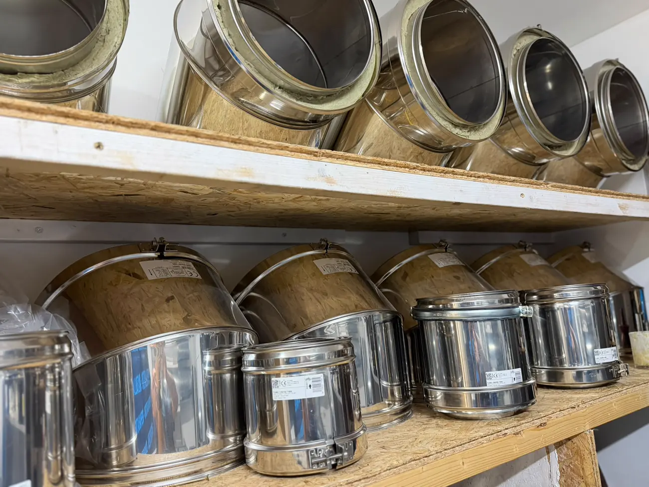 Coudes double paroi inox isolés en stock, empilés sur les étagères du dépôt