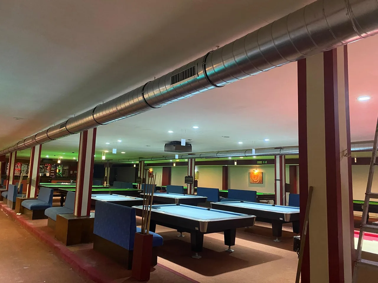 Long conduit d'extraction spiralé galvanisé installé au plafond d'une grande salle de jeux, avec bouches de reprise d'air réparties sur toute la longueur